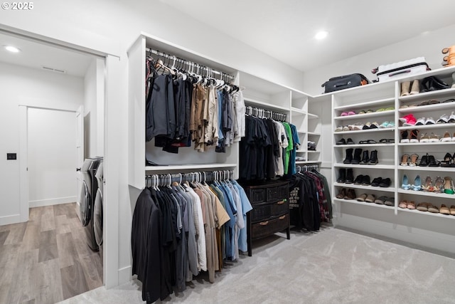 walk in closet with wood finished floors, visible vents, and washing machine and clothes dryer