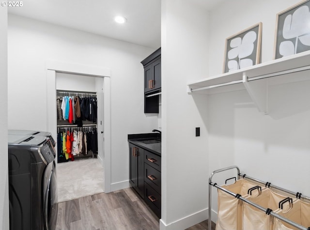 laundry area with washer and dryer, a sink, wood finished floors, cabinet space, and baseboards