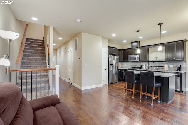 kitchen with a kitchen bar, appliances with stainless steel finishes, tasteful backsplash, pendant lighting, and a center island