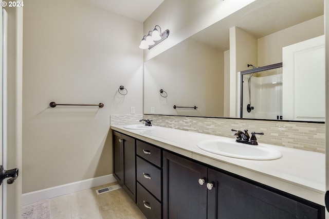 bathroom with tile patterned flooring, vanity, tasteful backsplash, and walk in shower