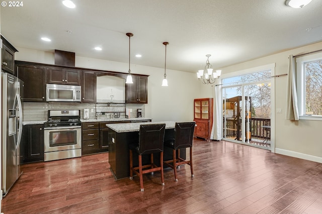 kitchen featuring hanging light fixtures, an inviting chandelier, a kitchen breakfast bar, a kitchen island, and appliances with stainless steel finishes