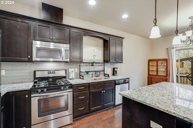 kitchen featuring dark brown cabinetry, sink, hanging light fixtures, and appliances with stainless steel finishes