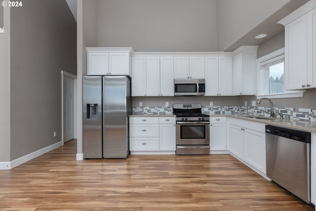 kitchen with light hardwood / wood-style floors, sink, stainless steel appliances, and white cabinets