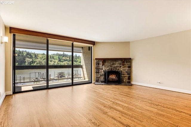 unfurnished living room with floor to ceiling windows, light hardwood / wood-style floors, and a fireplace