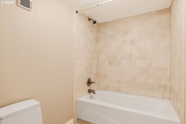 bathroom with toilet and tiled shower / bath