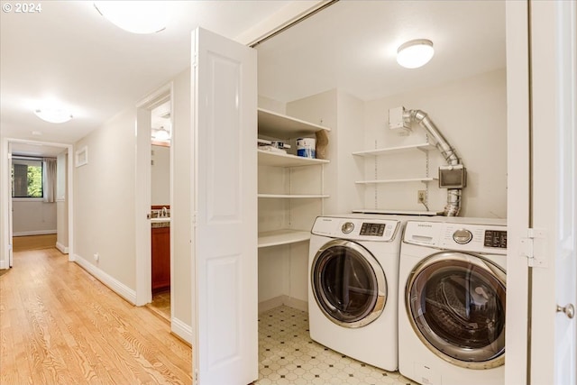 clothes washing area with washer and clothes dryer and light wood-type flooring