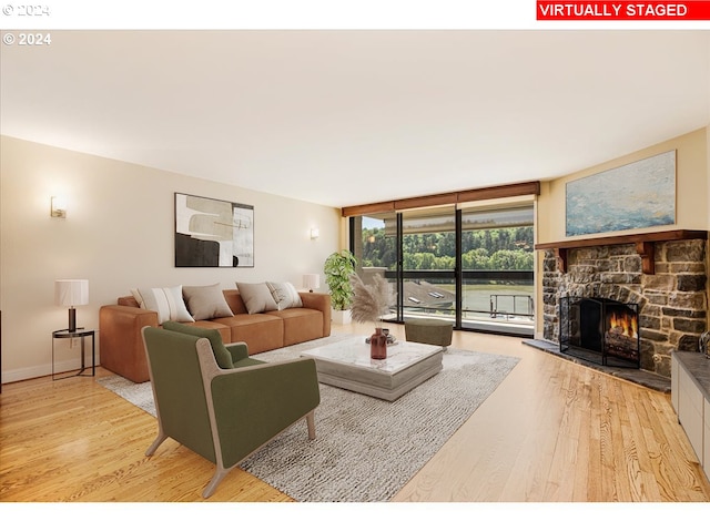 living room featuring a fireplace, light wood-type flooring, and expansive windows