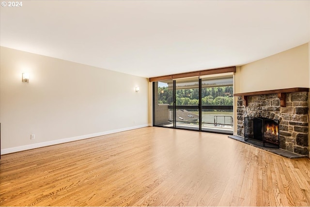 unfurnished living room with a fireplace, light hardwood / wood-style floors, and a wall of windows