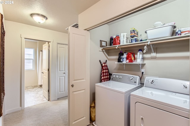 clothes washing area with light carpet, a textured ceiling, and separate washer and dryer