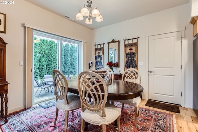 dining space with light hardwood / wood-style flooring and a notable chandelier