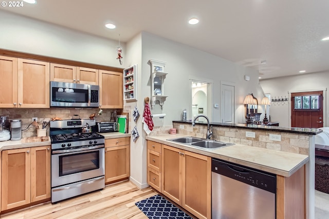 kitchen featuring light hardwood / wood-style floors, sink, kitchen peninsula, and stainless steel appliances