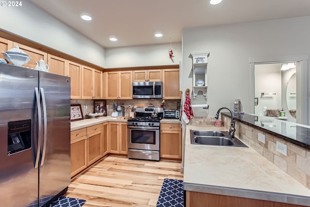 kitchen with sink, tasteful backsplash, light hardwood / wood-style floors, kitchen peninsula, and stainless steel appliances