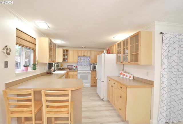 kitchen featuring white appliances, light brown cabinetry, ornamental molding, kitchen peninsula, and a breakfast bar area