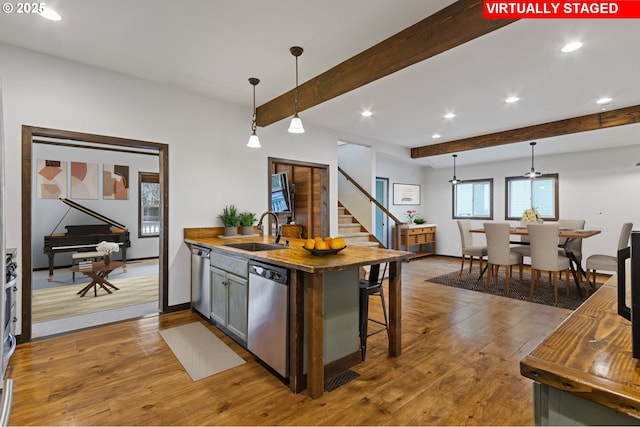 kitchen featuring sink, stainless steel dishwasher, decorative light fixtures, and a breakfast bar