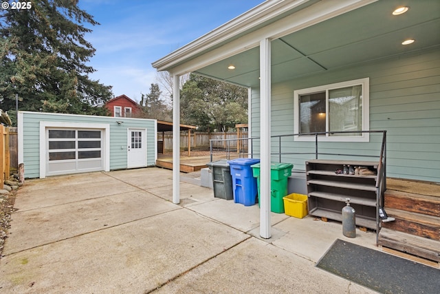 view of patio featuring a wooden deck, a garage, and an outdoor structure