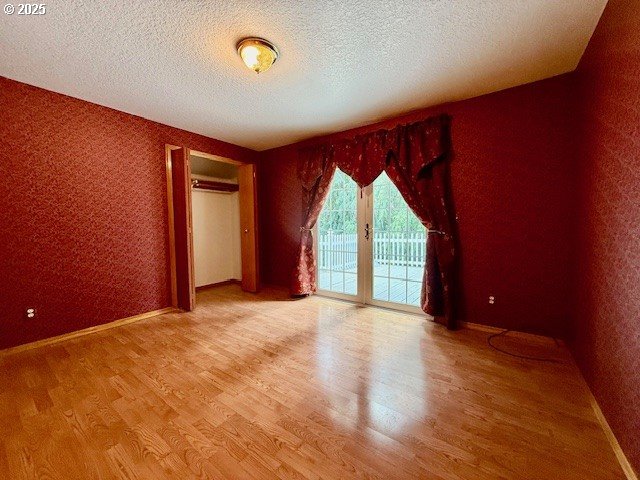 94504 Smokey Ln, Coquille, OR 97423 - empty room featuring baseboards, wood finished floors, and a textured ceiling