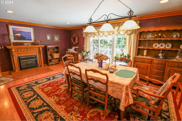 dining area featuring a textured ceiling, light wood-type flooring, and crown molding