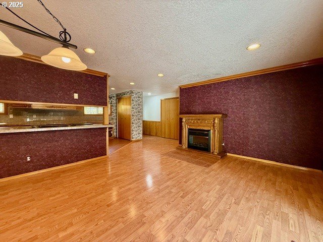 94504 Smokey Ln, Coquille, OR 97423 - unfurnished living room with a glass covered fireplace, a textured ceiling, crown molding, wainscoting, and wood finished floors