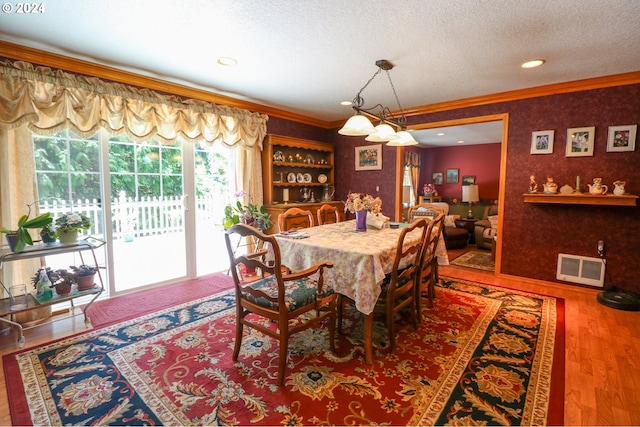 dining area featuring hardwood / wood-style floors, crown molding, and a textured ceiling