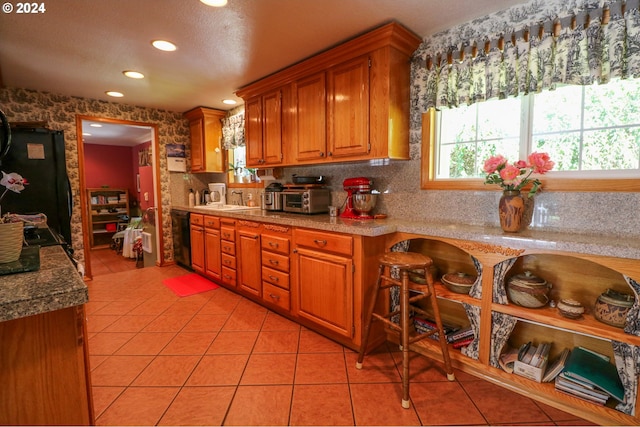 kitchen featuring black appliances, light tile patterned floors, and sink