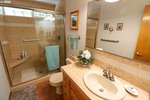 bathroom with decorative backsplash, hardwood / wood-style flooring, toilet, and an enclosed shower