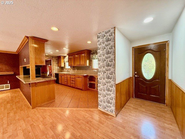 94504 Smokey Ln, Coquille, OR 97423 - kitchen featuring a peninsula, wainscoting, visible vents, and brown cabinetry