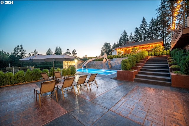 patio terrace at dusk featuring a fenced in pool