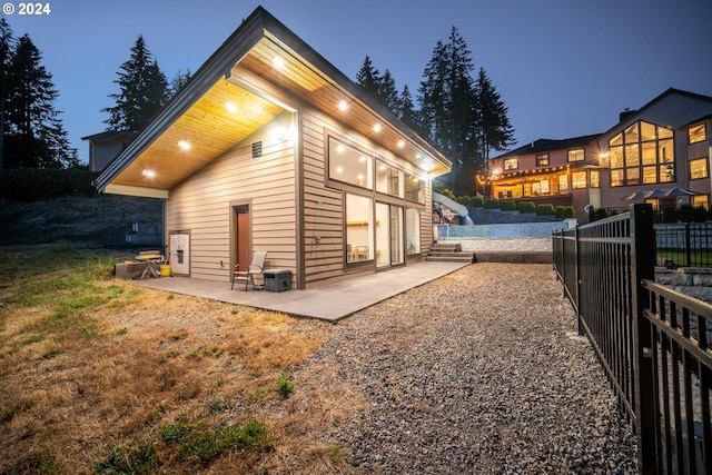 back house at dusk featuring a patio