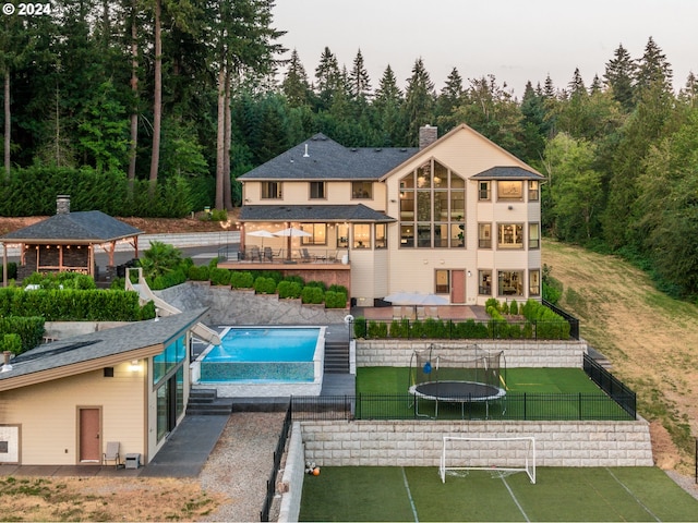 rear view of property featuring a patio area, a gazebo, a yard, and a trampoline