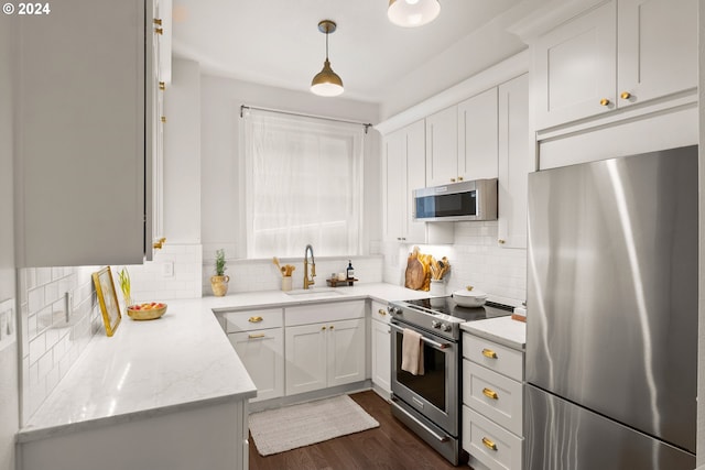 kitchen featuring white cabinets, appliances with stainless steel finishes, hanging light fixtures, and sink