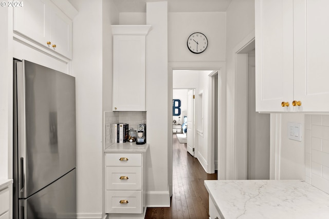 kitchen featuring white cabinets, stainless steel fridge, and light stone counters