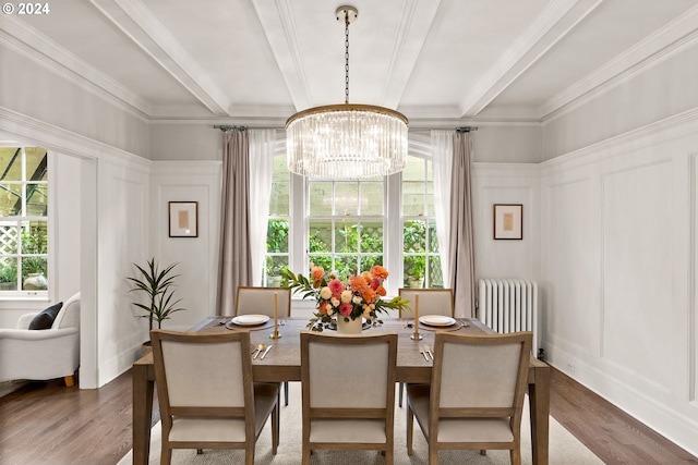 dining area with radiator, hardwood / wood-style flooring, ornamental molding, and a notable chandelier