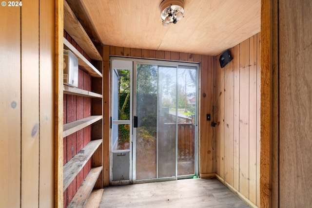 doorway featuring light wood-type flooring, wooden ceiling, and wood walls