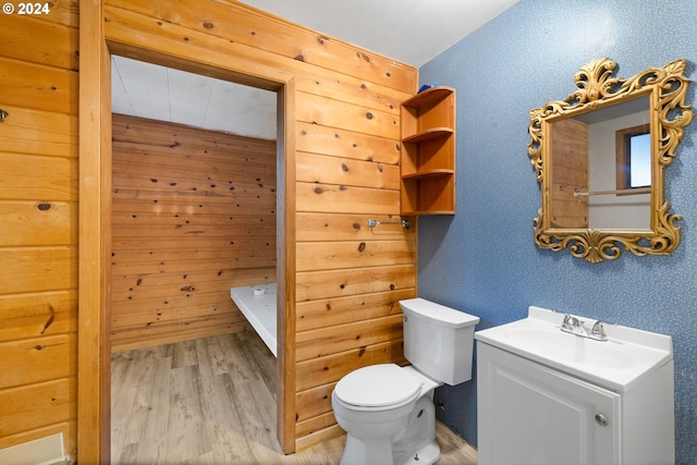 bathroom with wood-type flooring, vanity, toilet, and wooden walls