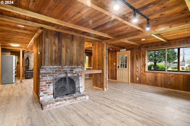 unfurnished living room featuring light hardwood / wood-style floors, wood ceiling, a fireplace, and wooden walls