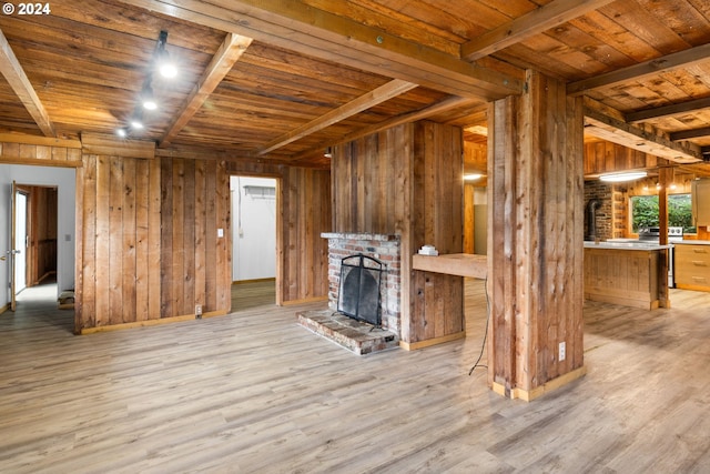 unfurnished living room with light hardwood / wood-style floors, wood walls, wood ceiling, and a fireplace