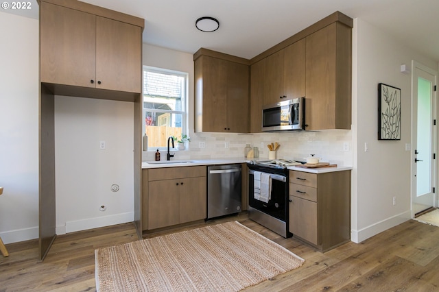 kitchen featuring backsplash, sink, light hardwood / wood-style floors, and appliances with stainless steel finishes