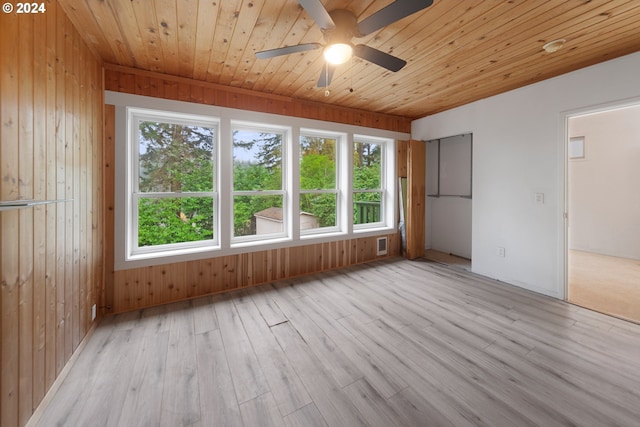 unfurnished room featuring wood walls, light wood-type flooring, and ceiling fan