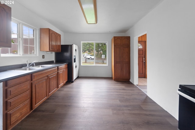 kitchen with dark wood-type flooring, stainless steel refrigerator with ice dispenser, sink, and range with electric stovetop