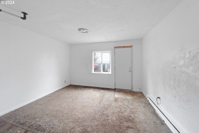 spare room with baseboard heating and carpet