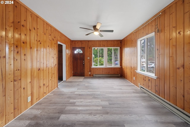 interior space with light hardwood / wood-style floors, baseboard heating, and wooden walls