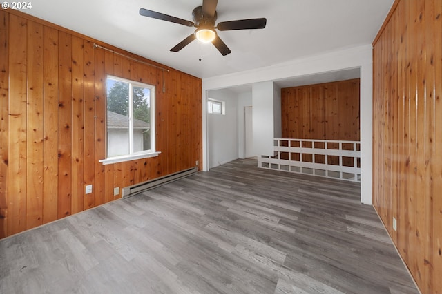 interior space featuring a baseboard heating unit, wood walls, hardwood / wood-style flooring, and ceiling fan