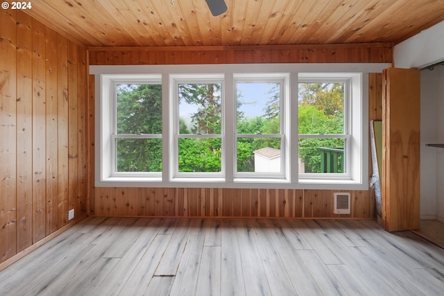 interior space featuring wood walls, a wealth of natural light, and light hardwood / wood-style floors