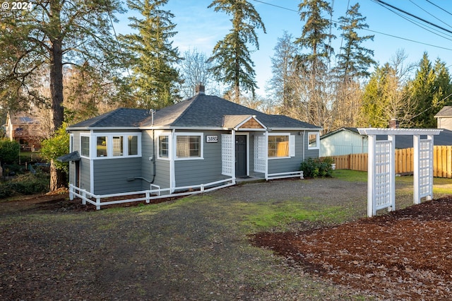 view of front of house with a shingled roof and fence