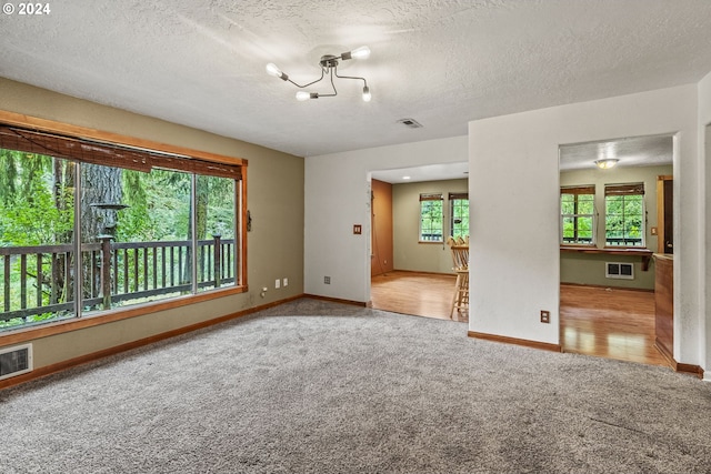 carpeted empty room with an inviting chandelier and a textured ceiling