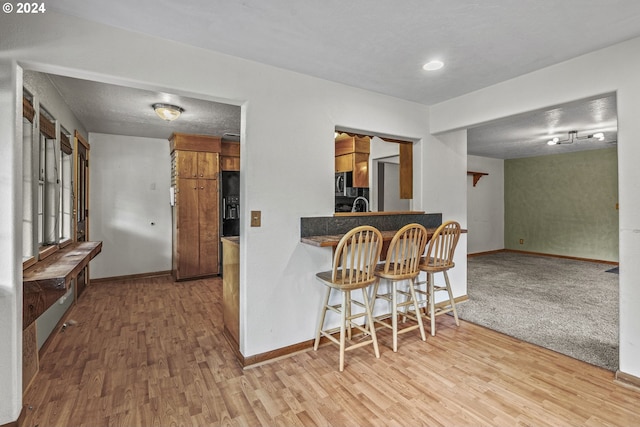 kitchen featuring light wood-type flooring, a textured ceiling, and a breakfast bar area