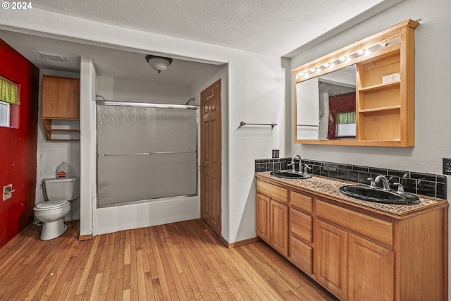 bathroom with vanity, an enclosed shower, a textured ceiling, hardwood / wood-style flooring, and toilet