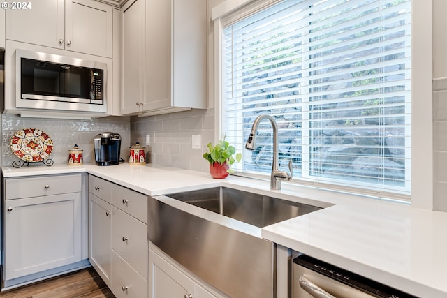 kitchen with sink, backsplash, wood-type flooring, and stainless steel appliances