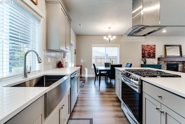 kitchen featuring dark hardwood / wood-style flooring, hanging light fixtures, a chandelier, extractor fan, and appliances with stainless steel finishes