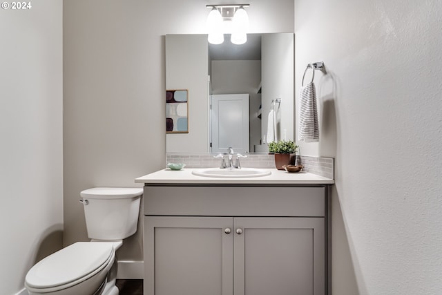 bathroom with vanity, toilet, and decorative backsplash